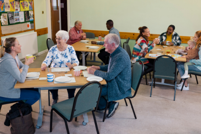 People sat around tables in a community centre