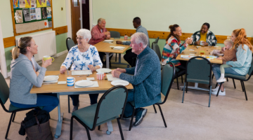 People sat around tables in a community centre